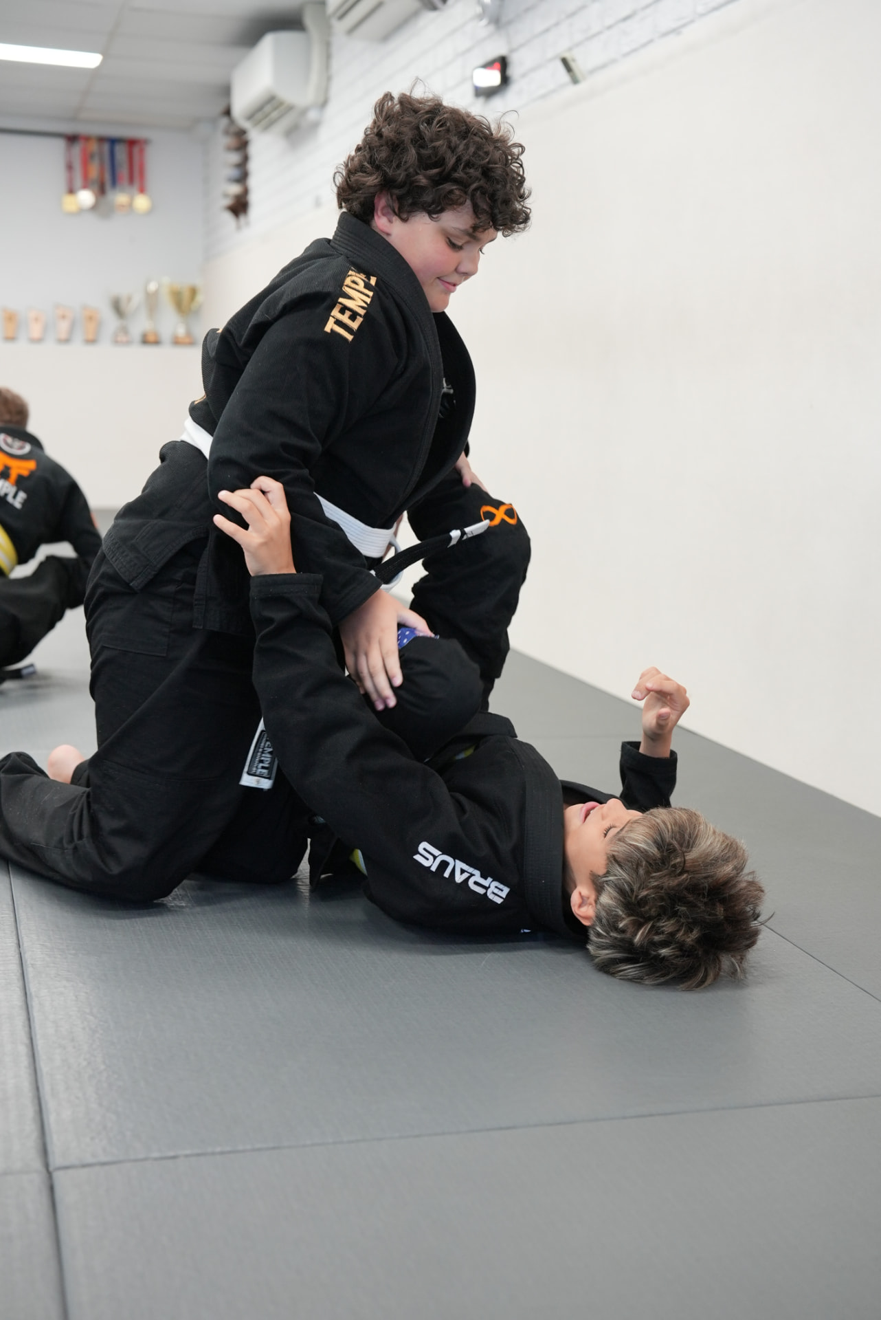 Two Big Kids students in black Temple gis drilling a guard pass on the mats