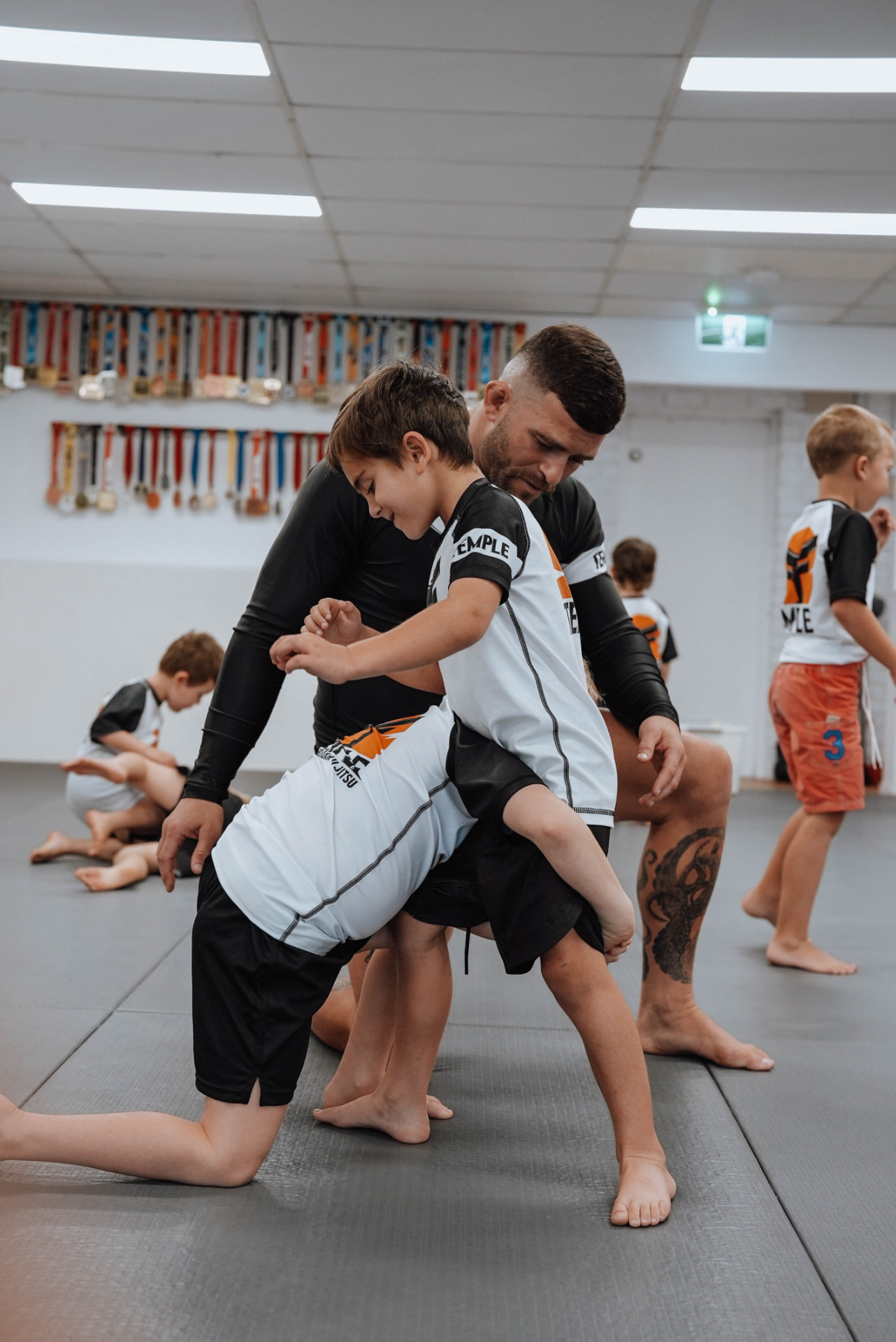 Coach guiding Little Kids through a takedown drill in a Jiu-Jitsu class at Temple BJJ