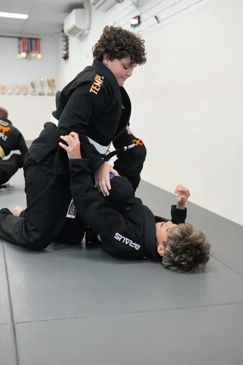 Two Big Kids students in black Temple gis drilling a guard pass on the mats