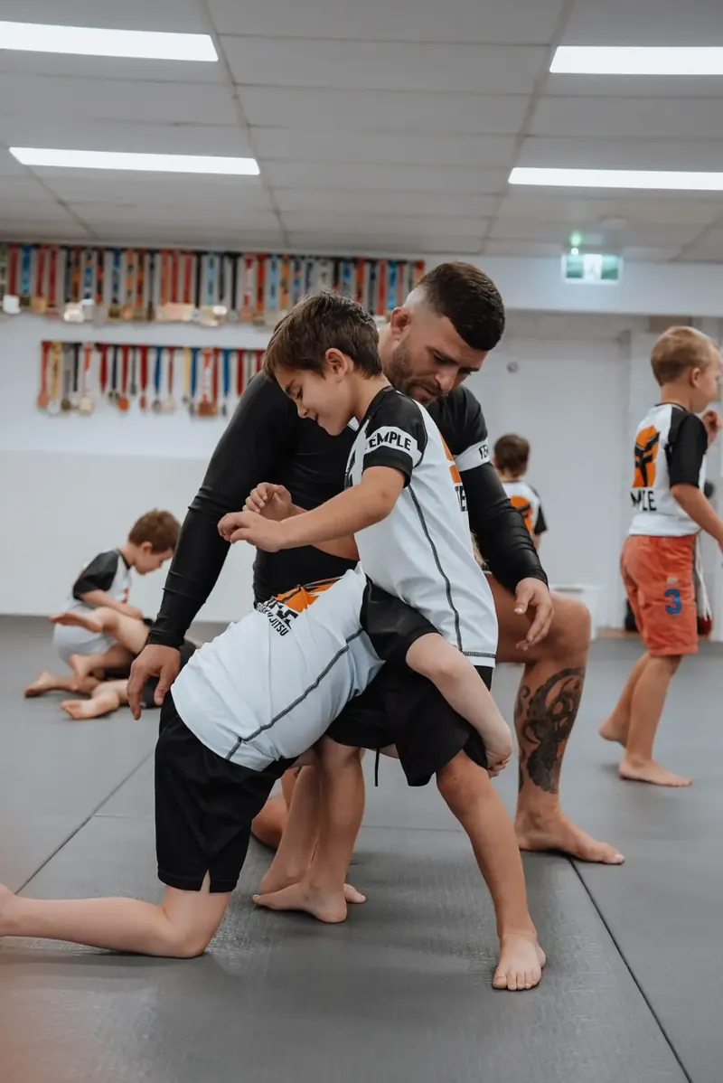 Coach guiding Little Kids through a takedown drill in a Jiu-Jitsu class at Temple BJJ