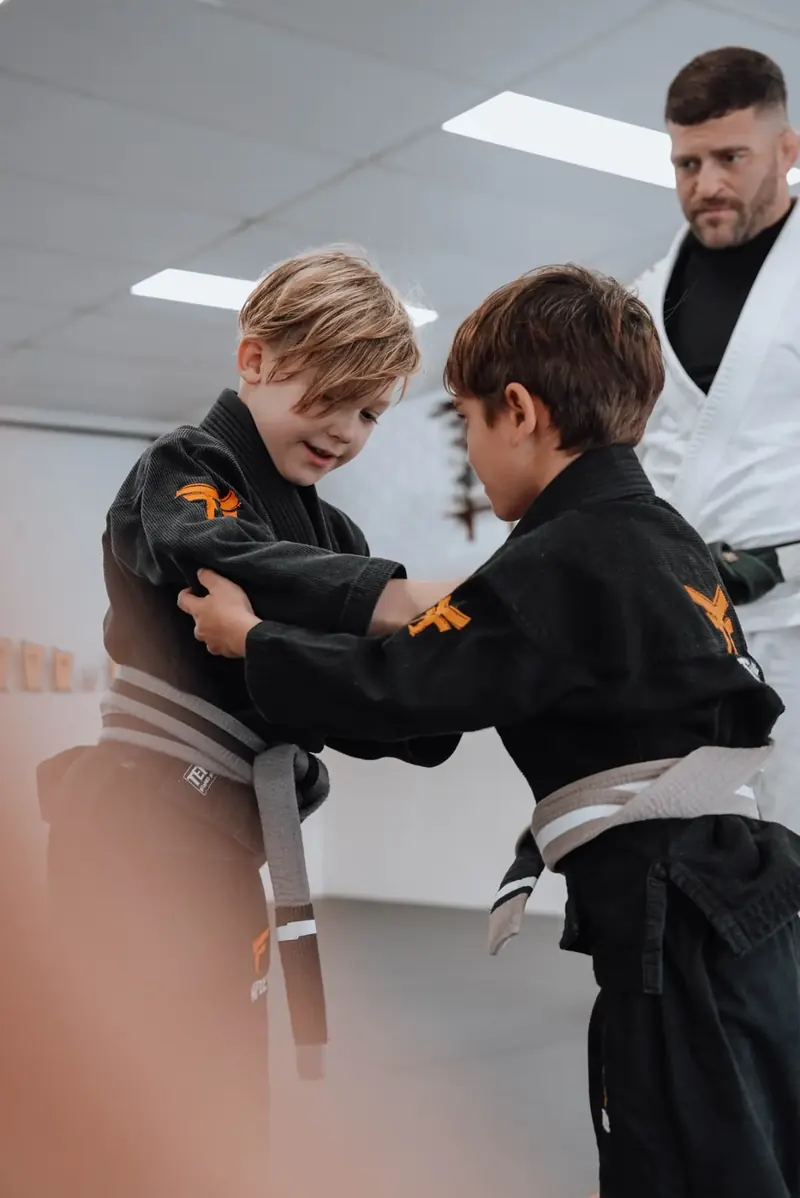Two kids drilling while a coach supervises at Temple BJJ